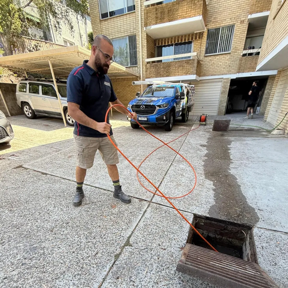 Antons plumber feeding drain-cleaning equipment into an outdoor drain