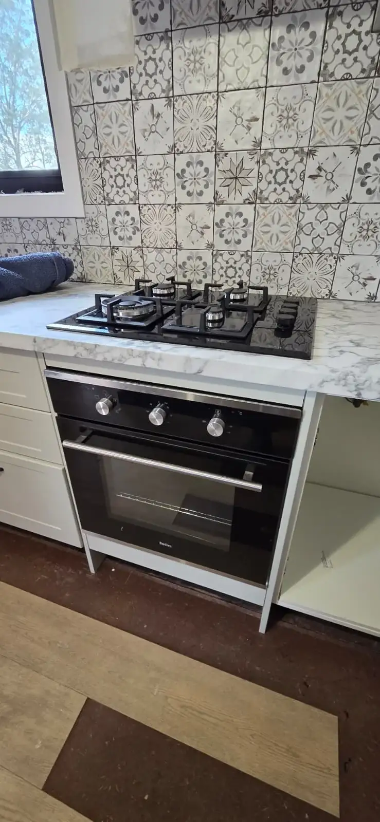 Installed black gas cooktop and oven in a residential kitchen