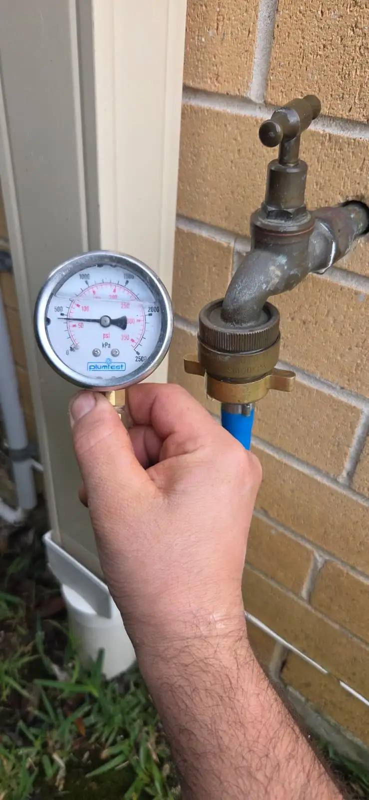 Water pressure gauge connected to an outdoor tap during a residential leak test