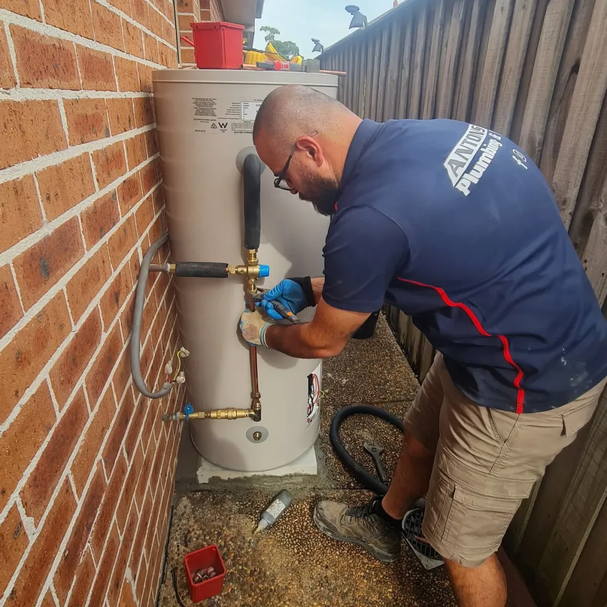 Carlingford plumber working on pipe connections to an outdoor hot water storage tank